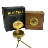 A gold-colored metal compass with an engraved religious message, presented alongside its wooden box and black packaging with the brand name 'Portho'.